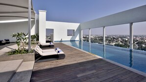 A rooftop infinity pool with lounge chairs and a city view. - Radisson Blu Coimbatore (Coimbatore)