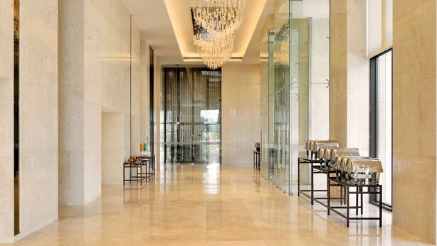 A spacious hallway with a modern chandelier, glass walls, and a seating area with tables and chairs. - Radisson Blu Coimbatore (Coimbatore)