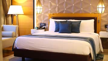 A hotel room with a large bed, a bedside table, a lamp, and a chair.