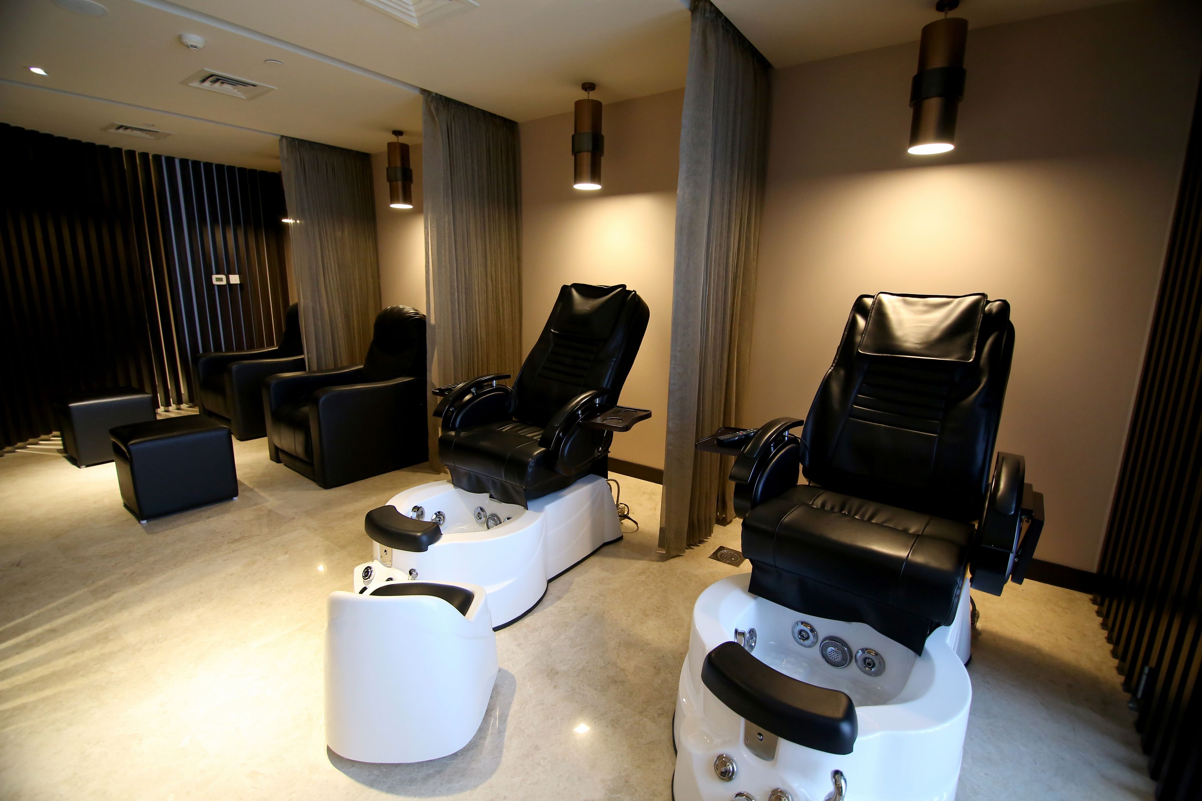 A spa room with two massage chairs, a white foot bath, and a small table.