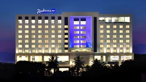 A hotel with a prominent 'Radisson' sign, multiple floors, and a central blue-lit section. - Radisson Blu Coimbatore (Coimbatore)