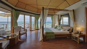 A room with a bed, a chair, a table, and a view of the ocean. - Safari Island Resort (Mushimasgali)