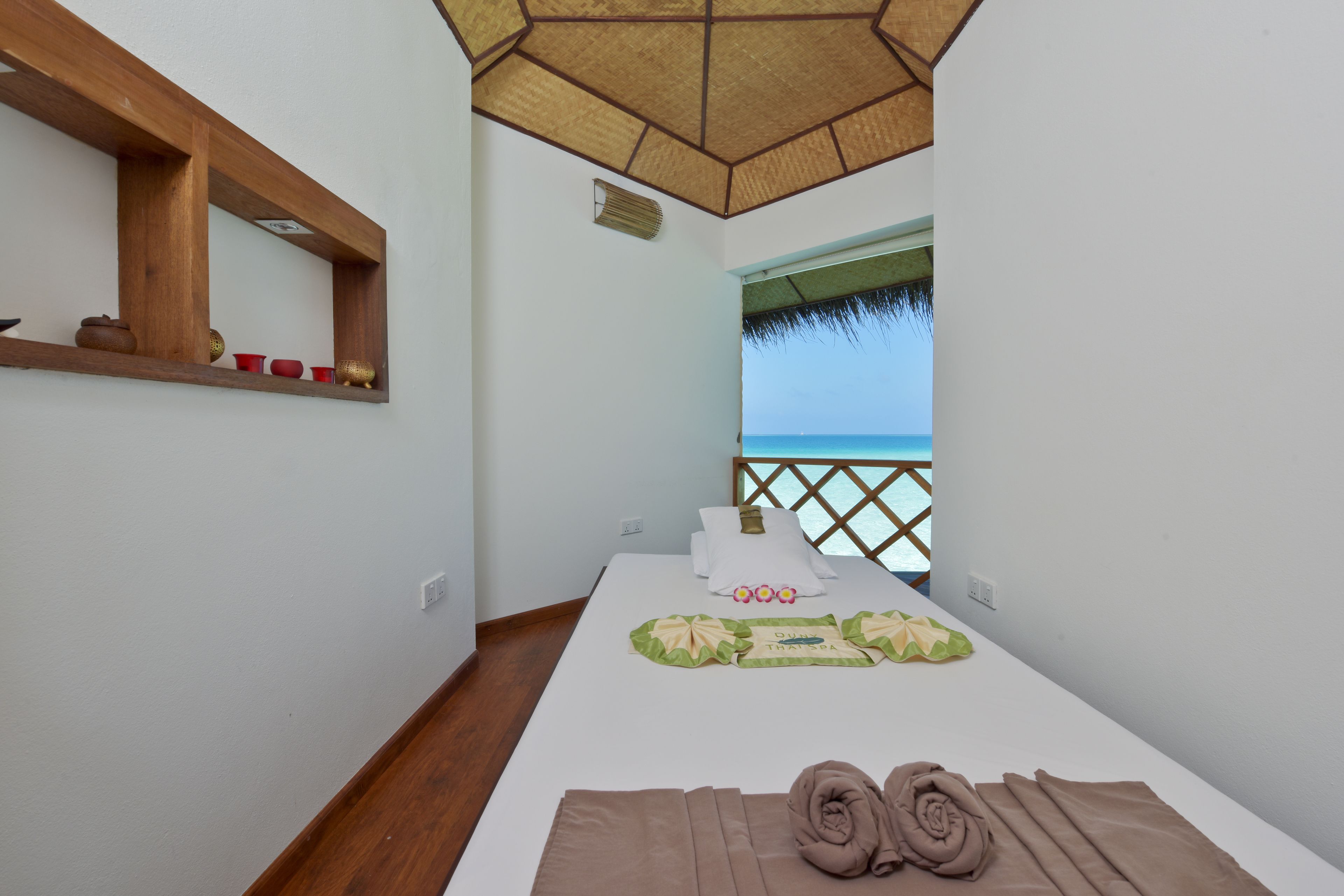 Habitación de hotel con cama, una pequeña estantería con adornos, un espejo y vista al mar.