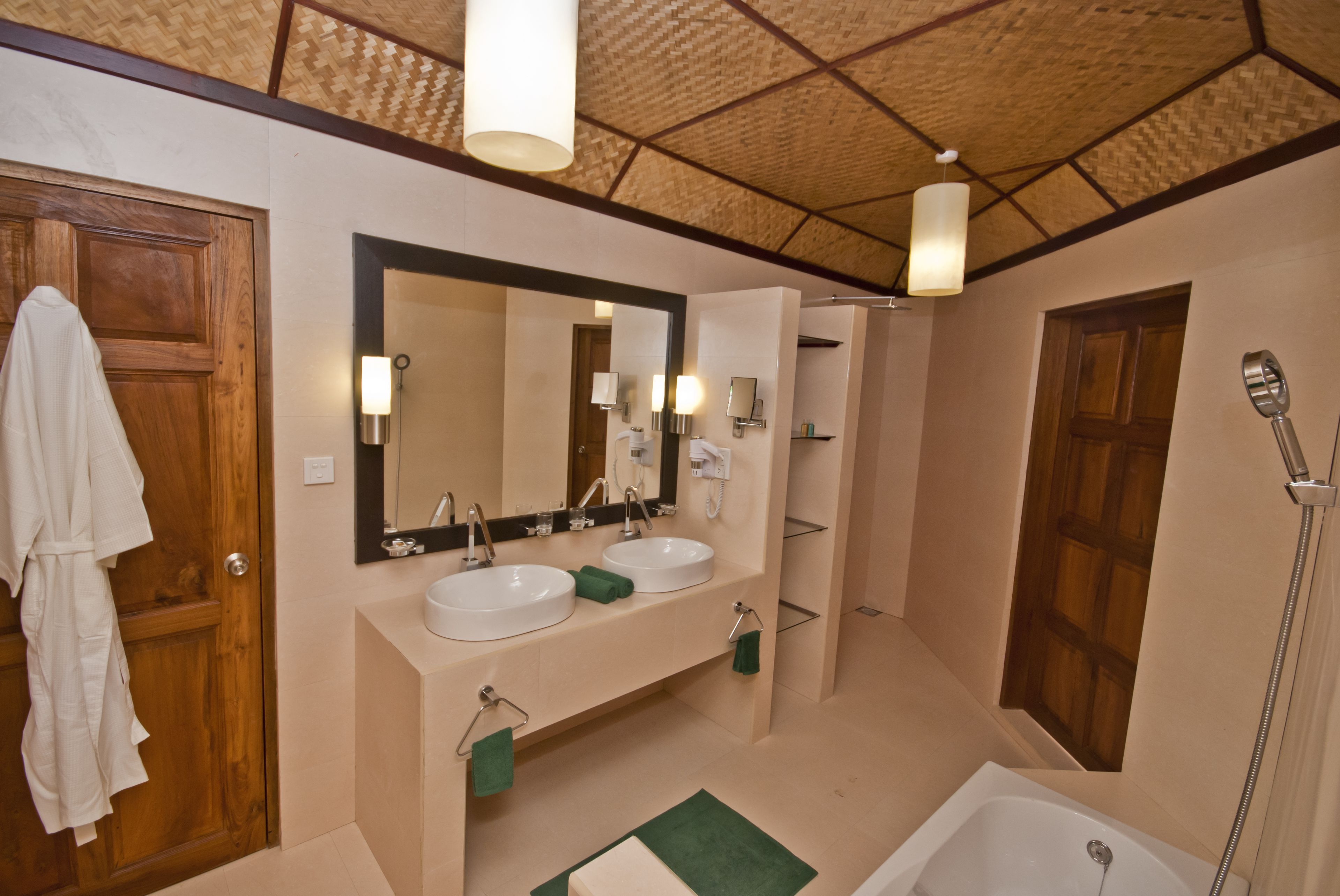 Un baño con dos lavamanos, un espejo grande, una ducha y una puerta de madera.