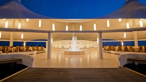 An outdoor dining area with a central fountain, surrounded by tables and chairs, under a large tent structure. - Safari Island Resort (Mushimasgali)