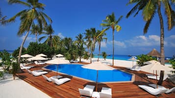 Alberca al aire libre, sombrillas en la alberca y camastros