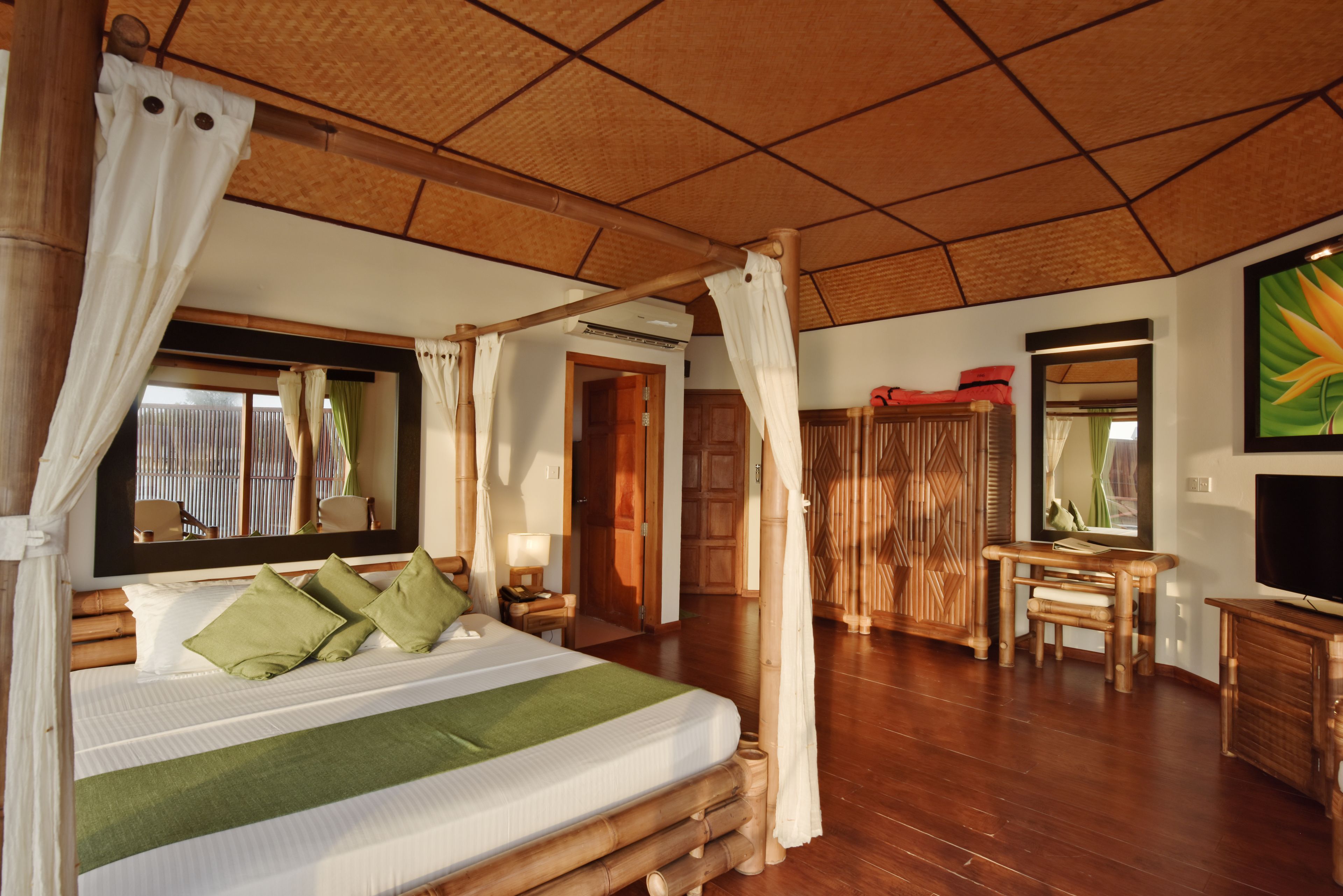 Un dormitorio amplio con una cama grande, cabecera de madera, un espejo, un escritorio y un televisor.