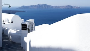 A white-walled hotel with a sign reading "HOTEL THIRESAS" and a view of the sea and distant islands. - Thireas Hotel (Santorini)