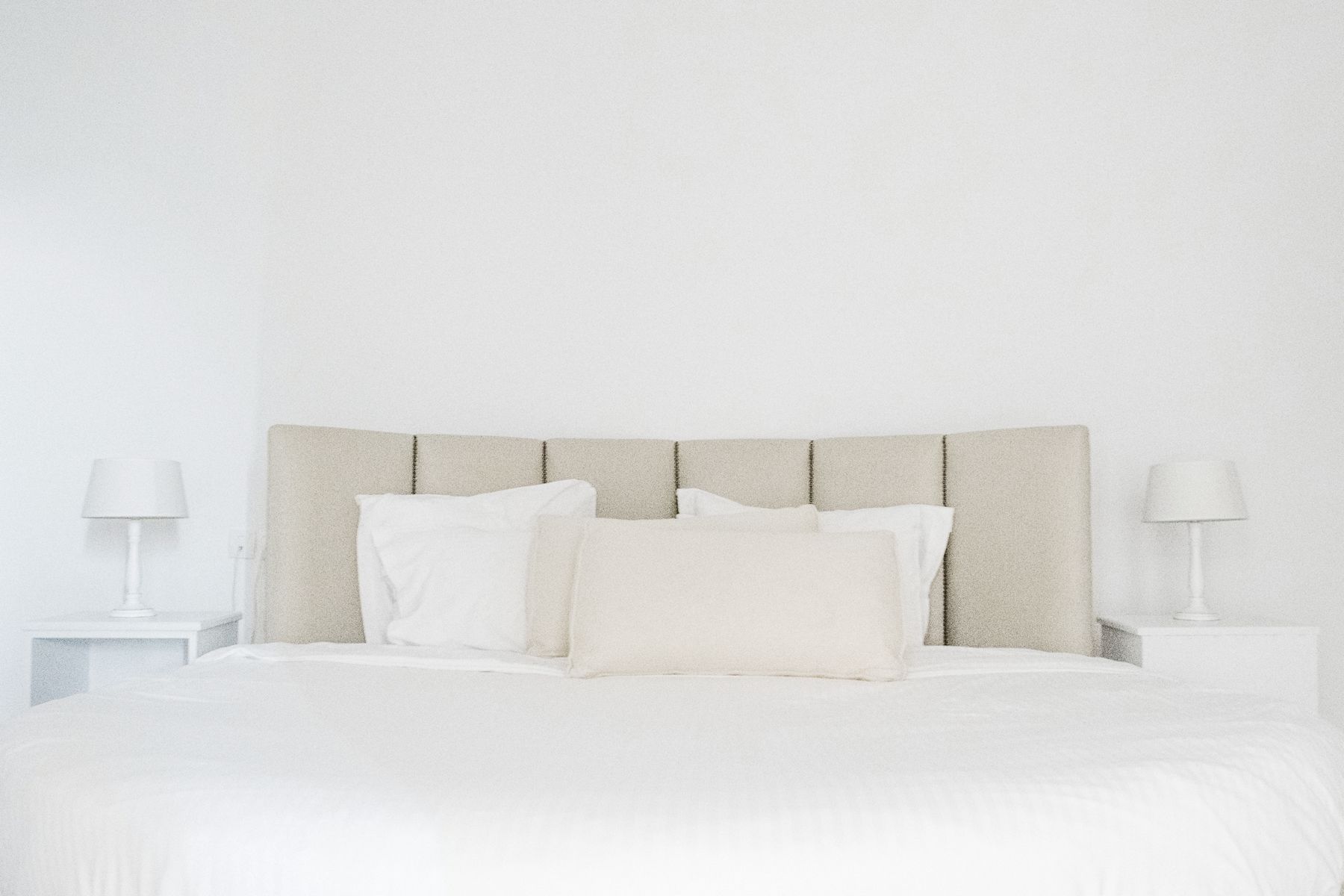 A bed with a headboard, two bedside tables, and lamps.