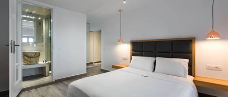 Un dormitorio moderno con una cama grande, un vestidor y lámparas colgantes.