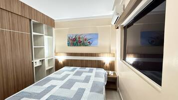 Un dormitorio con cama, un cuadro de flores, un armario y una ventana.