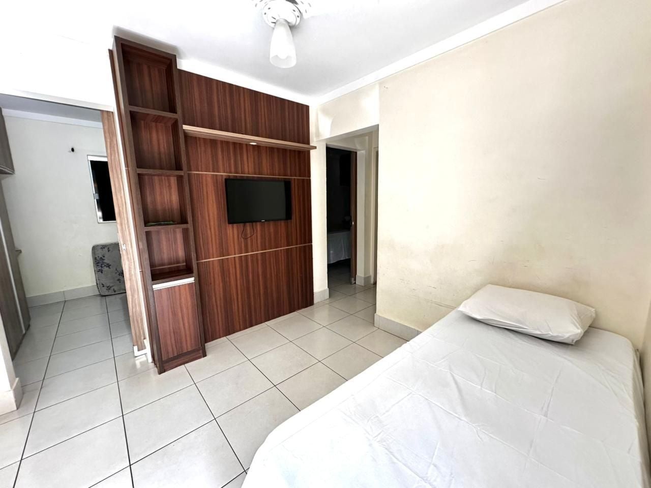 Ein Schlafzimmer mit einem Bett, einem an einer Holzwand montierten Fernseher und einem gefliesten Boden.