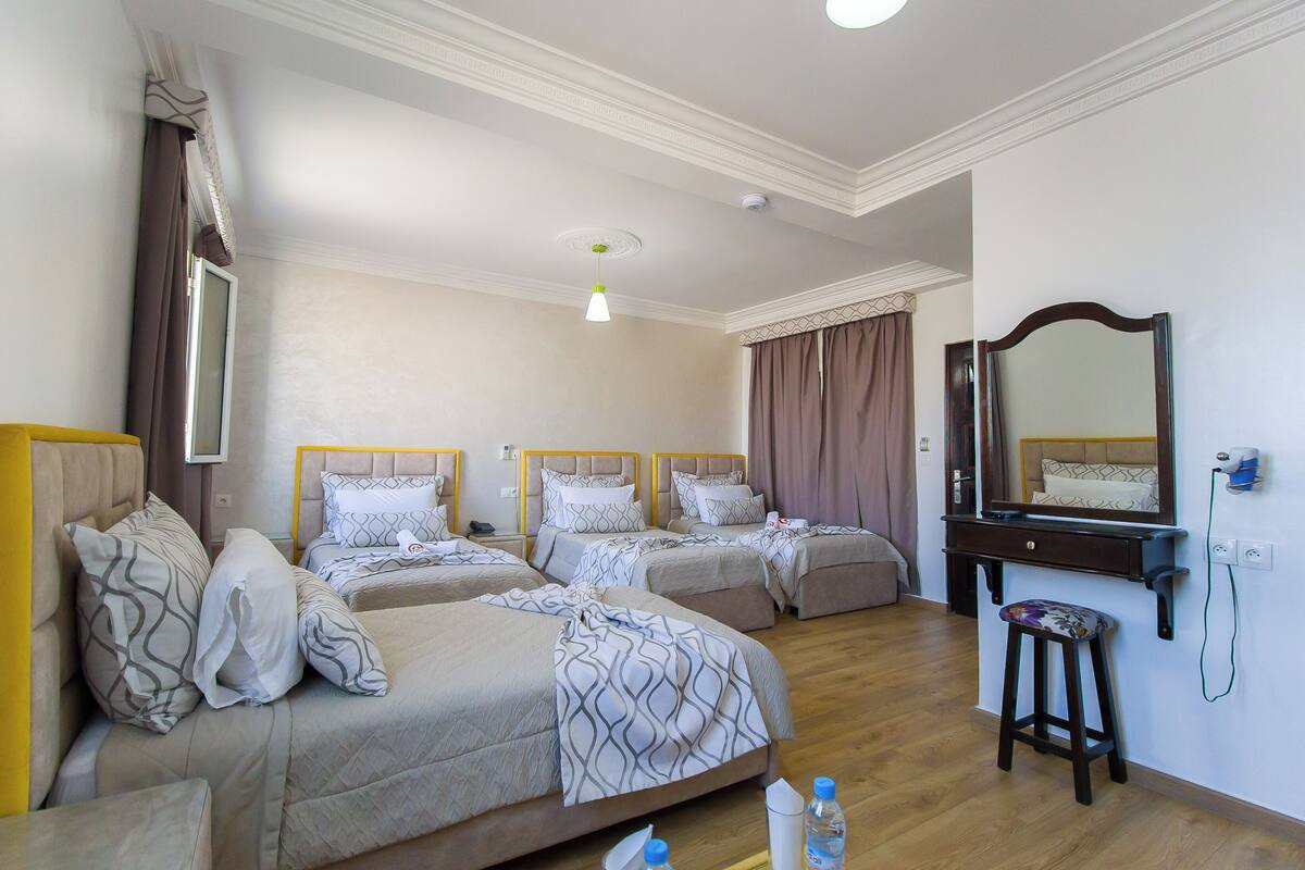 Habitación de hotel con dos camas, un escritorio, un espejo y un taburete.