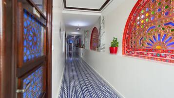 A hallway with patterned flooring, decorative wall panels, and a potted plant.