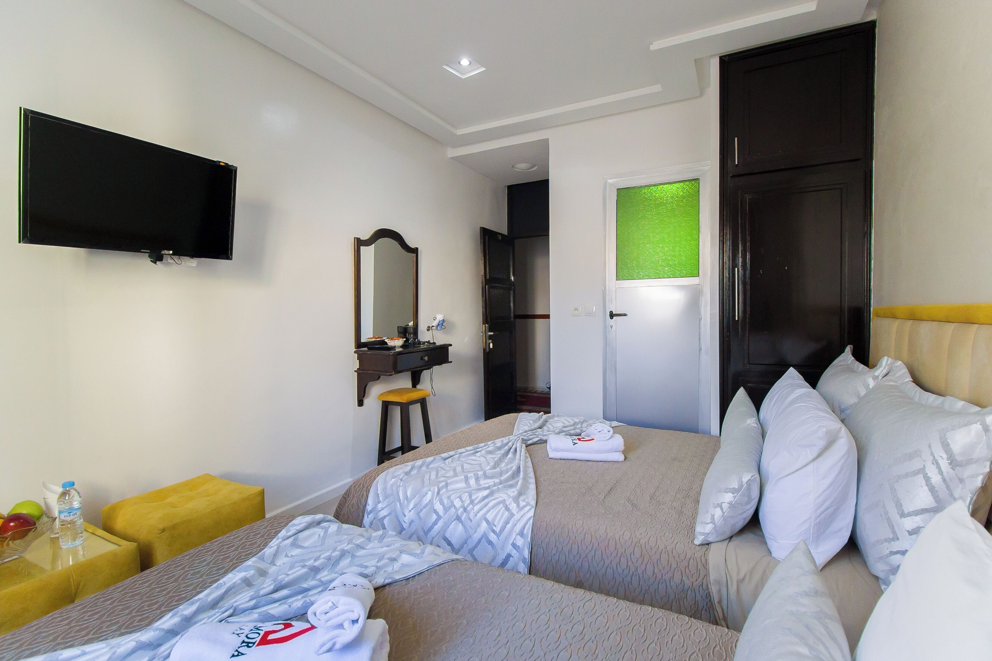 A hotel room with a bed, a TV mounted on the wall, a desk with a chair, and a mirror.
