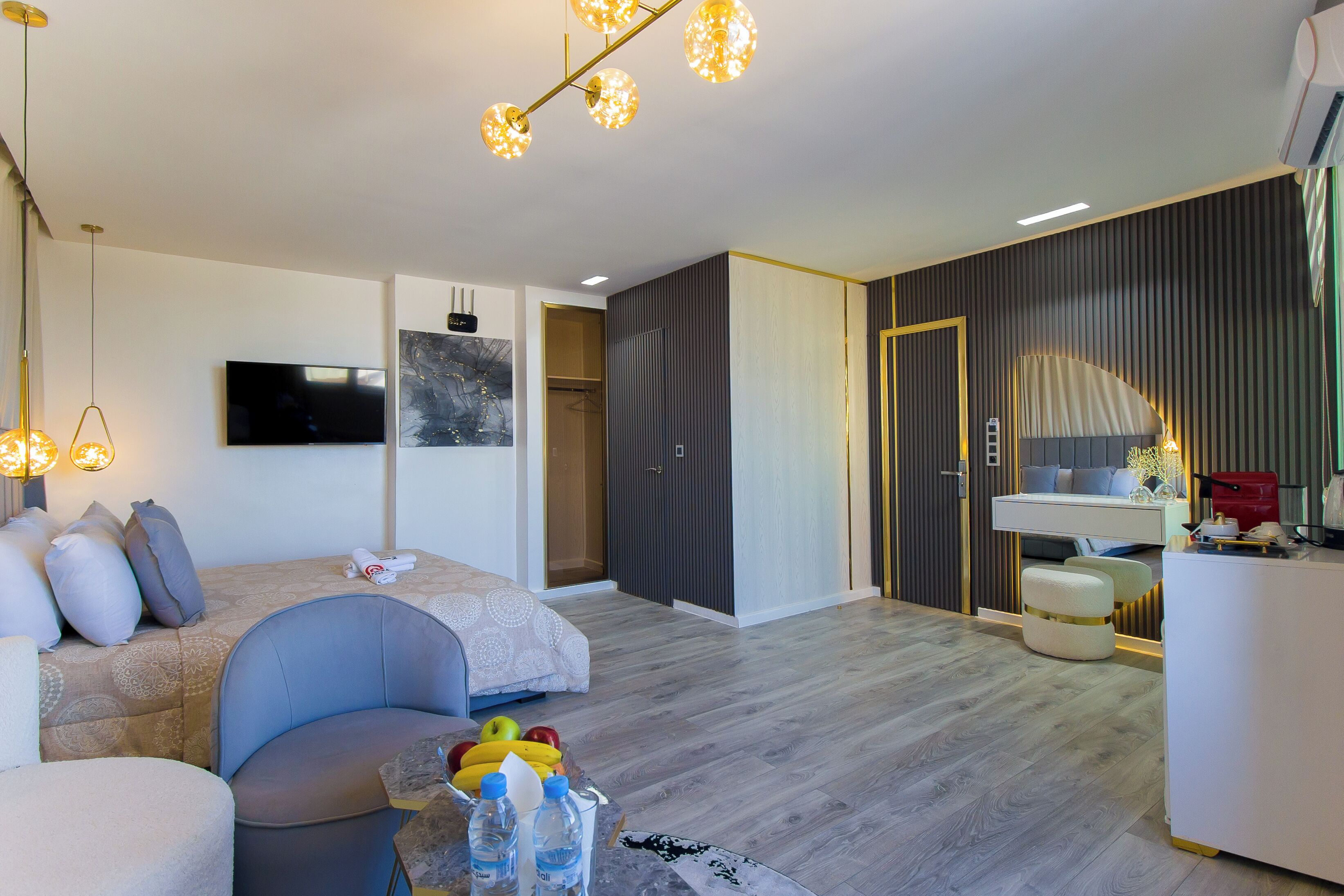 A modern hotel room with a bed, seating area, and a small kitchenette.