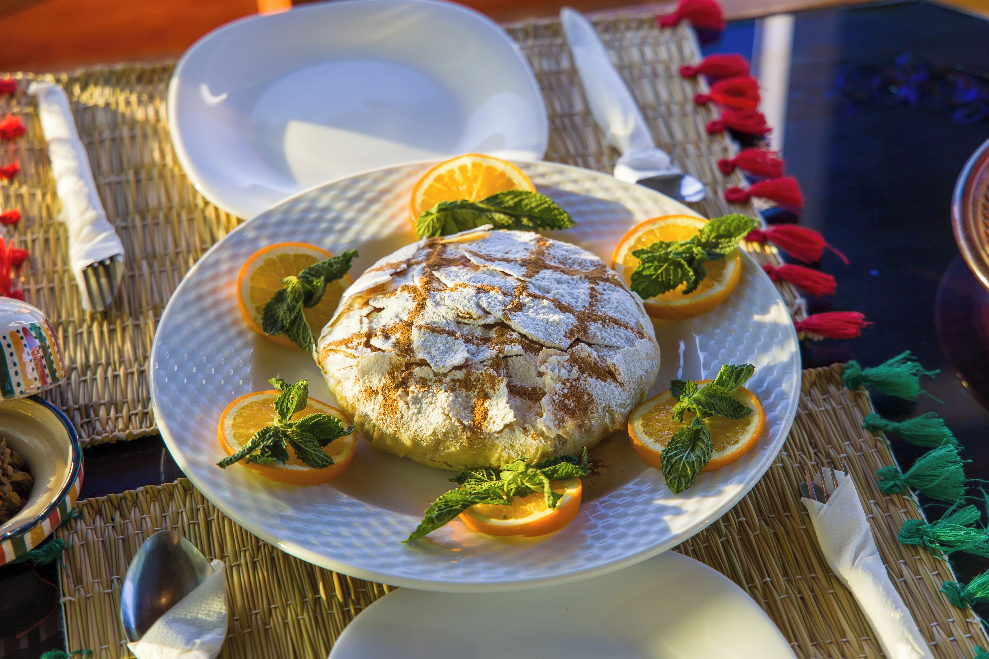 A dessert on a plate with mint leaves and orange slices.