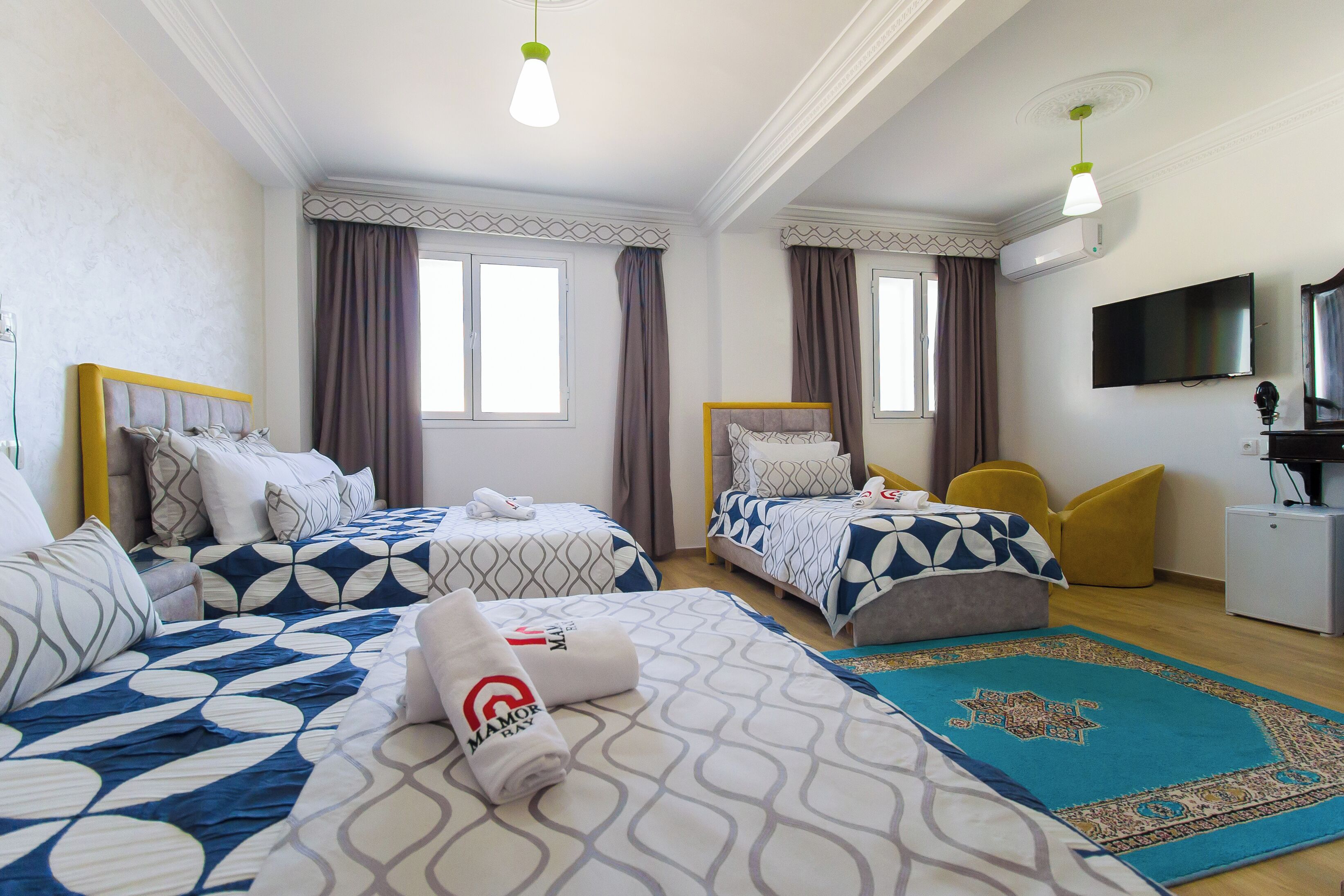 A hotel room with two beds, a television, and a desk.