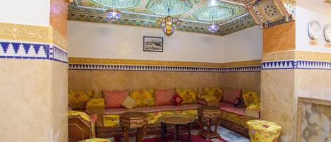 A traditional room with a sofa set, a chandelier, and patterned walls.