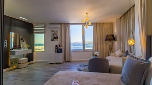 A modern hotel room with a large bed, a sitting area, a desk, and a view of the city. - MAMORA BAY (Tangier)