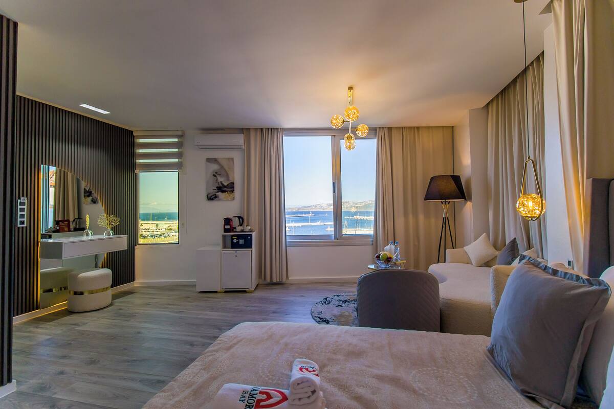 Una habitación de hotel moderna con una cama grande, una zona de estar, un escritorio y vistas a la ciudad.