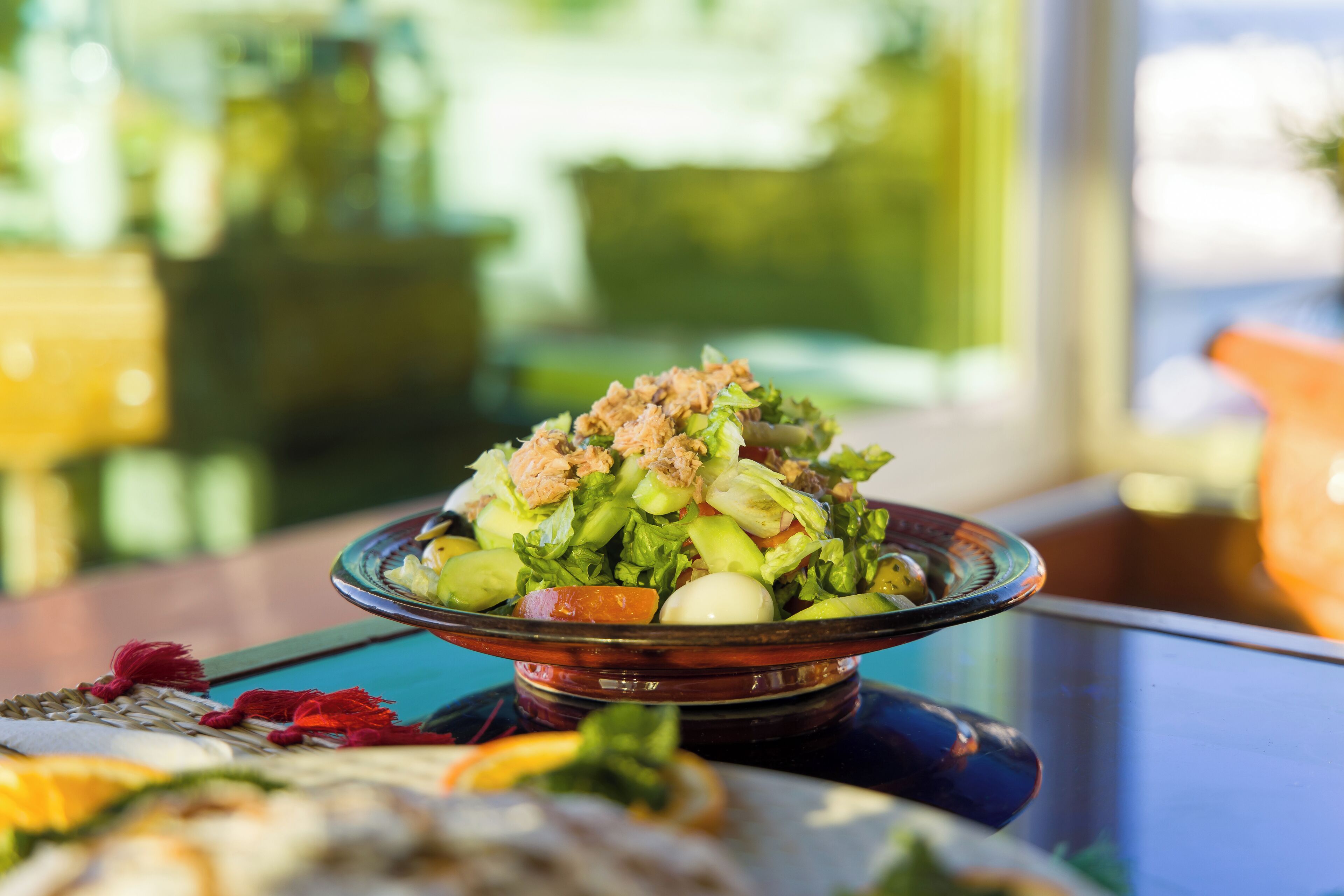 A salad on a glass plate with a blurred background.