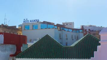 Un hotel llamado "HOTEL MAMORA" con un diseño moderno, que destaca un letrero prominente y grandes ventanales.