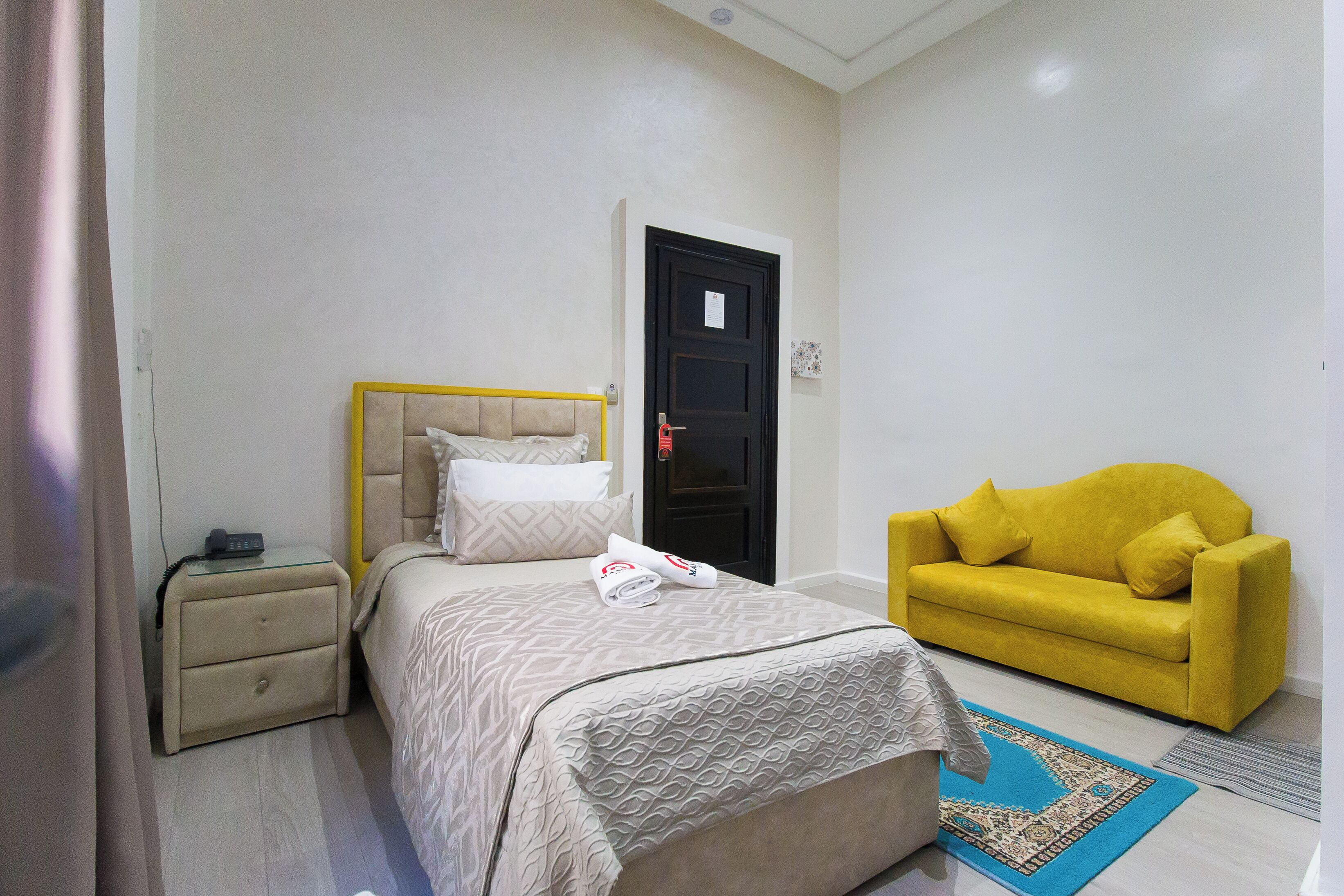 Una camera da letto con un letto, un comodino e un divano giallo.