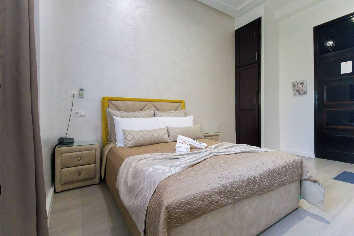 Un dormitorio ordenado con cama, mesitas de noche y armario.