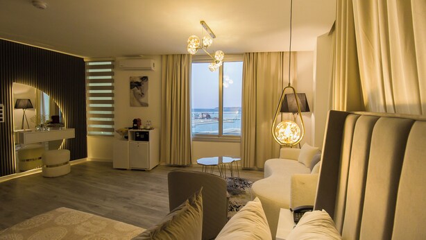 A modern hotel room with a large window, a sofa, a dining area, and a small kitchen. - MAMORA BAY (Tangier)