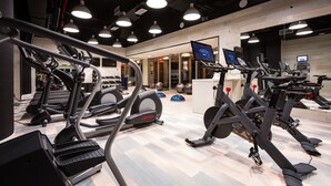 Een fitnessruimte met loopbanden, elliptische trainers en trainingsballen.