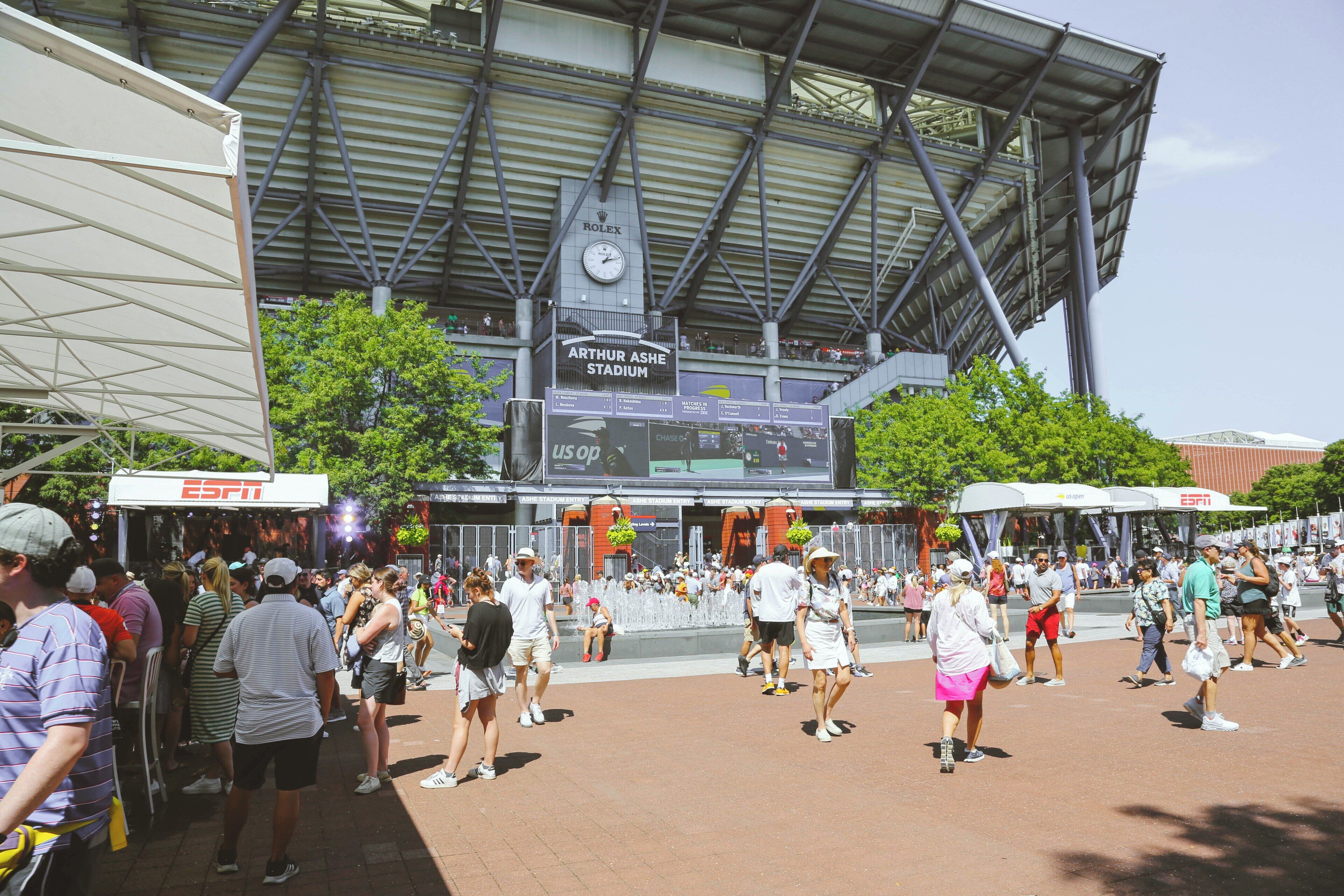 A stadium with a clock and advertisements, surrounded by a crowd of people.