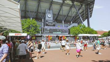 A stadium with a clock and advertisements, surrounded by a crowd of people.