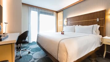 Een hotelkamer met een groot bed, een bureau, een stoel en een nachtkastje.