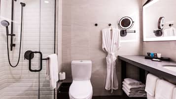 A modern bathroom with a glass-enclosed shower, a toilet, a vanity with a mirror, and neatly stacked towels.