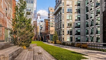 Una calle urbana moderna con una acera pavimentada, edificios con grandes ventanales y un pequeño espacio con césped.