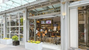 Een moderne bar met glazen wanden, terraszitplaatsen en diverse planten.