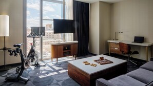 Een moderne hotelkamer met een groot raam, een bureau, een stoel, een loopband en een salontafel.