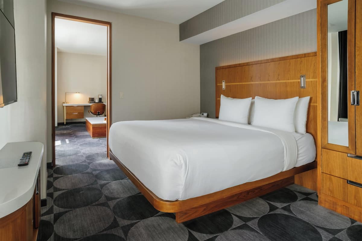 Ein Hotelzimmer mit einem großen Bett, einem Holzkopfteil, einem Nachttisch und einem Spiegel.