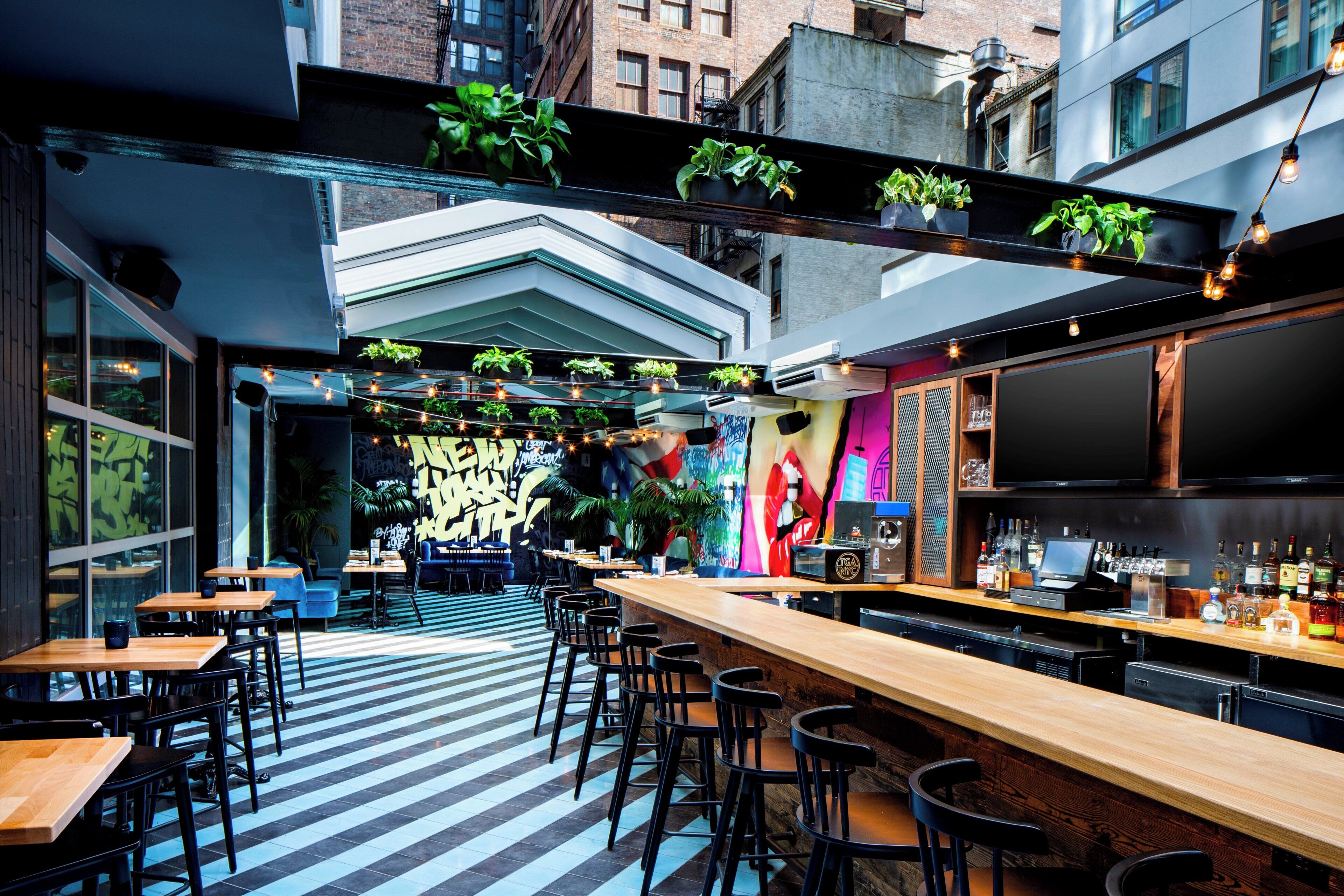 Un espace bar doté d’un long comptoir, de nombreux tabourets et d’un bar bien garni de bouteilles.