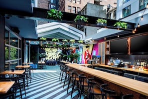 A bar area with a long counter, multiple stools, and a bar stocked with bottles.