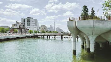 Un paseo marítimo con un puente moderno, un horizonte urbano al fondo y un cielo despejado.