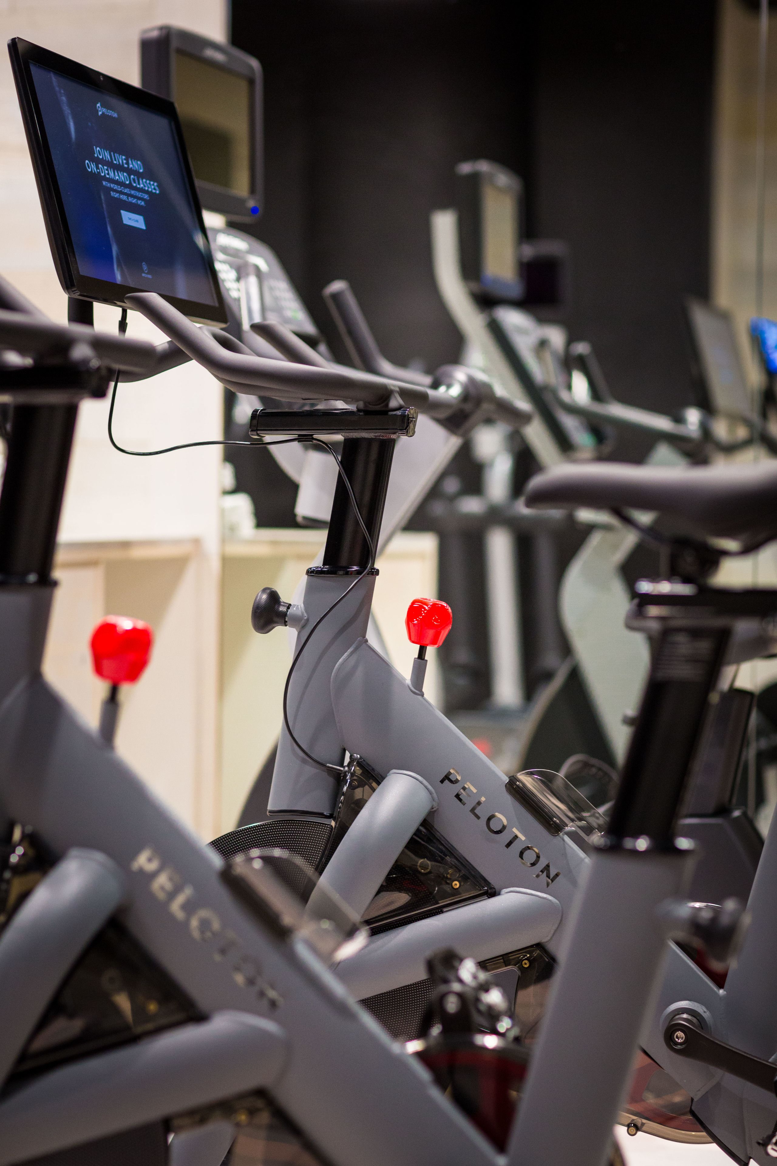 A row of stationary bikes with digital screens displaying a message.