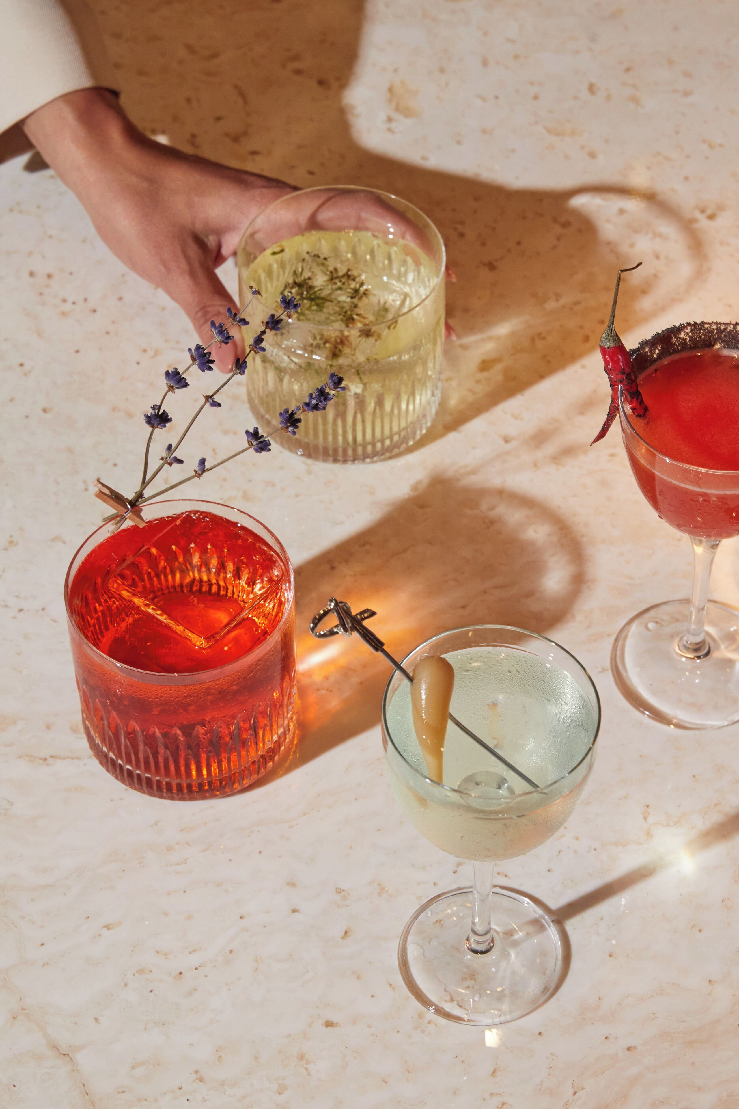 Tres vasos de bebidas de colores distintos sobre una superficie de mármol.