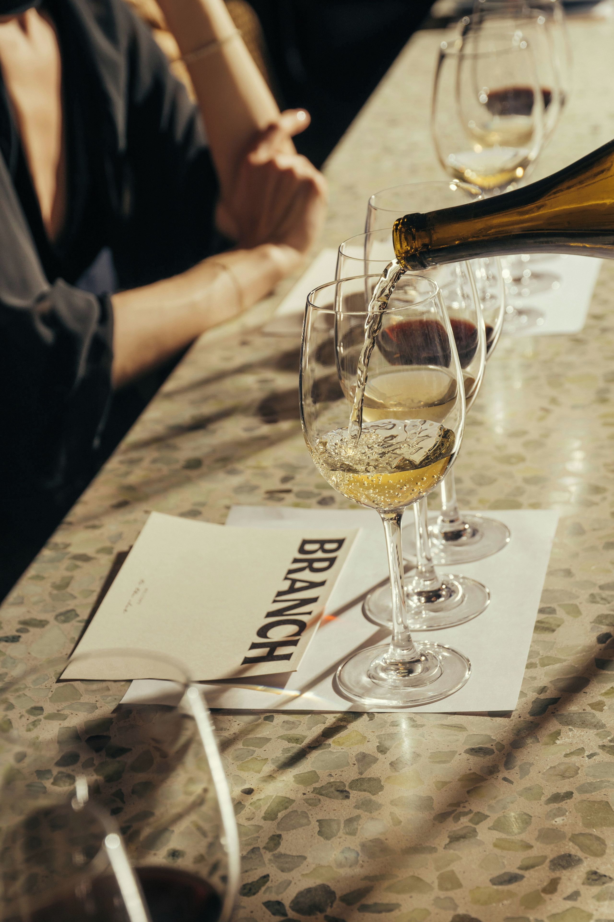 A table with wine glasses and a bottle being poured into one of them.