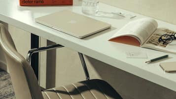 Een modern bureau met een laptop, boeken, een bril en een pen.