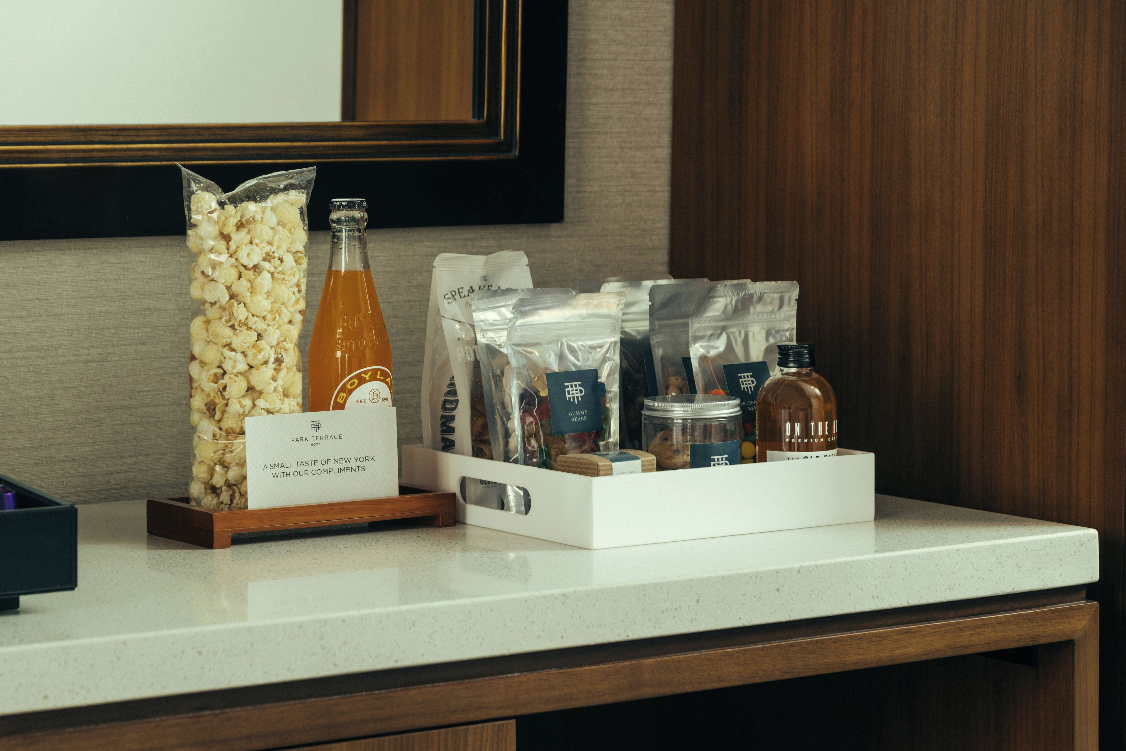 Et hotelreceptionsområde med en snackbod, der tilbyder popcorn, sodavand og forskellige pakker med snacks.