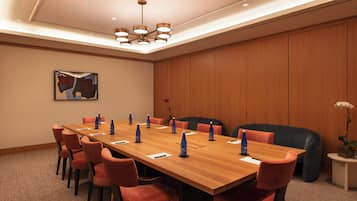Ein Konferenzraum mit einem langen Holztisch, roten Stühlen und einer modernen Kristallleuchtre.