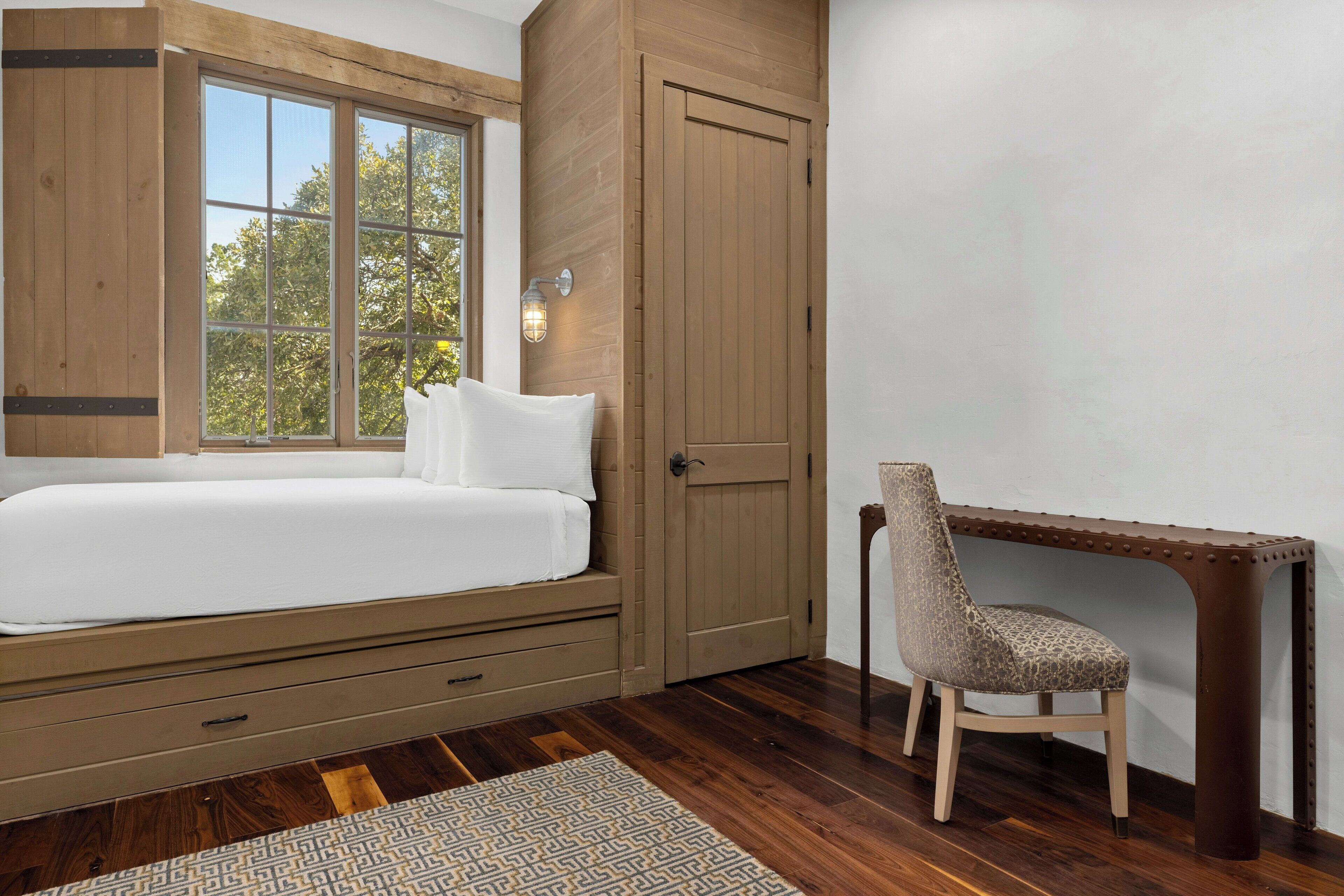 A bedroom with a bed, a desk, and a chair.