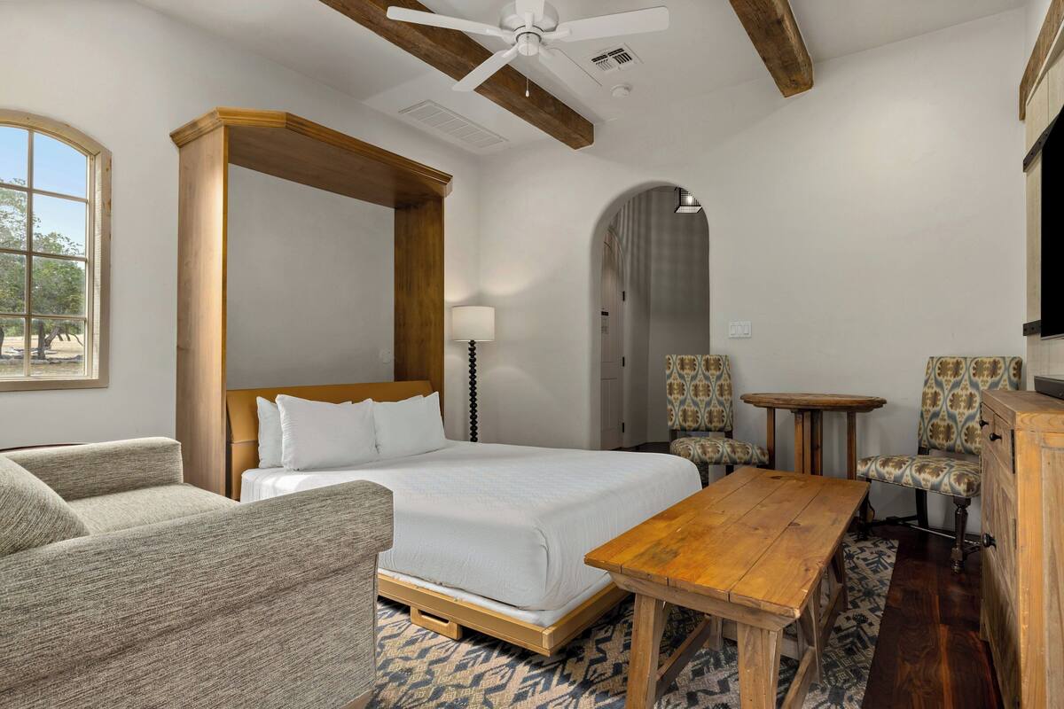 Een hotelkamer met een groot bed, een houten tafel, een bank en een bureau.